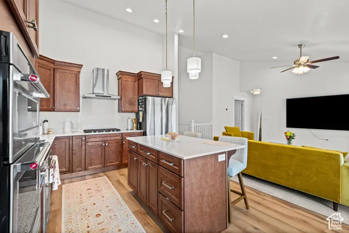 Kitchen featuring wood-finish cabinetry, stainless steel appliances, and a central island with countertop seating