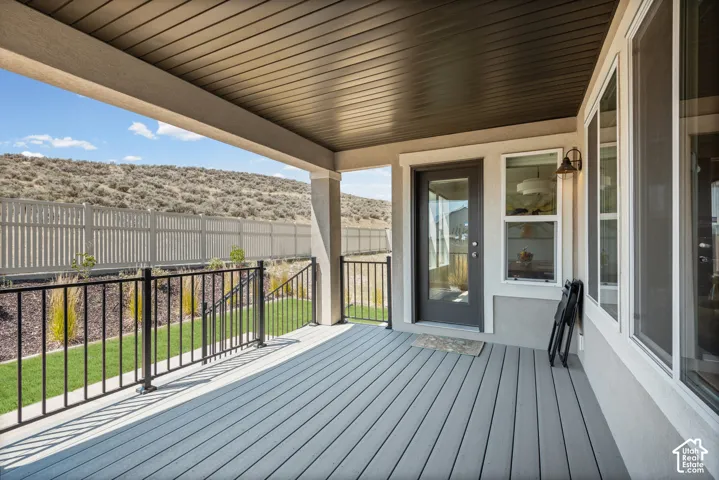 Covered patio with composite decking, black metal railings, and a glass-paneled exterior door