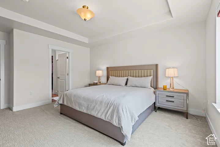 Spacious primary bedroom with neutral wall finishes, recessed ceiling detail, and abundant natural light from large windows