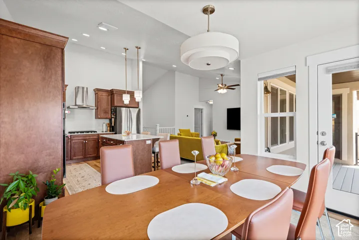 Open-concept living space featuring high ceilings, a kitchen with stainless steel appliances, a center island, and wood-finish cabinetry