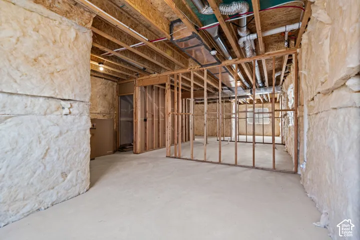 Unfinished basement featuring exposed wood framing, concrete flooring, and ceiling-mounted utilities