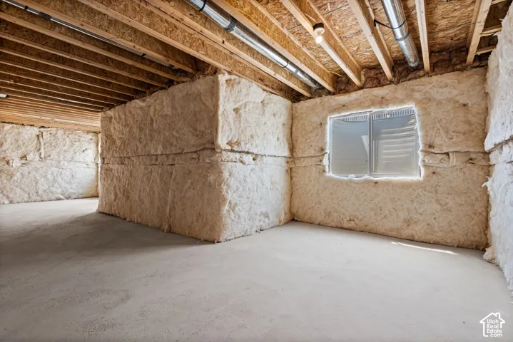 Unfinished basement with concrete flooring and exposed wood ceiling joists
