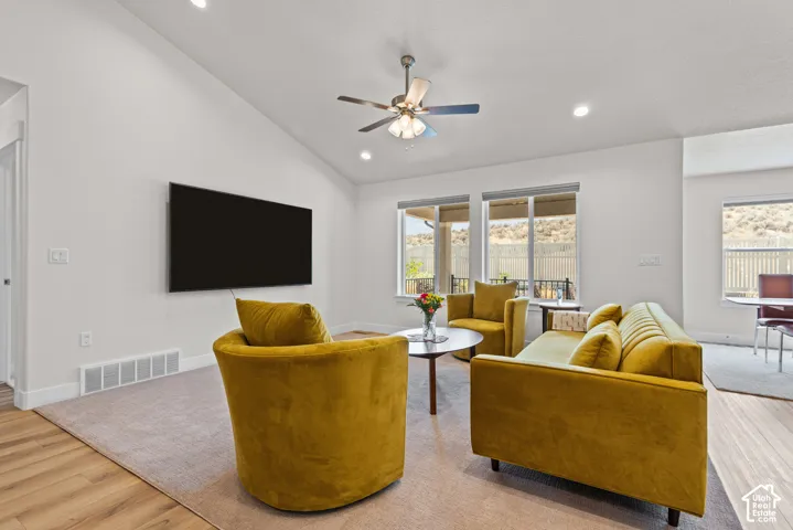 Vaulted ceiling with recessed lighting and a ceiling fan, large windows, and wood-finish flooring