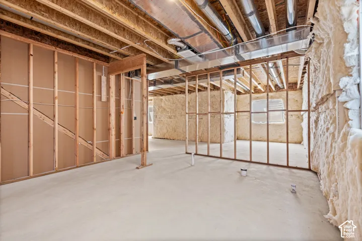 Unfinished interior space featuring exposed wood framing, concrete flooring, spray foam insulation, and visible HVAC ductwork