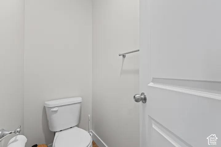 White porcelain toilet, chrome towel bar, and a white paneled door with brushed nickel hardware