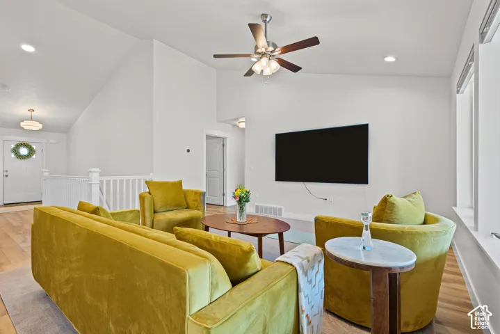Vaulted ceilings, wood-finish flooring, white walls, ceiling fan, and recessed lighting