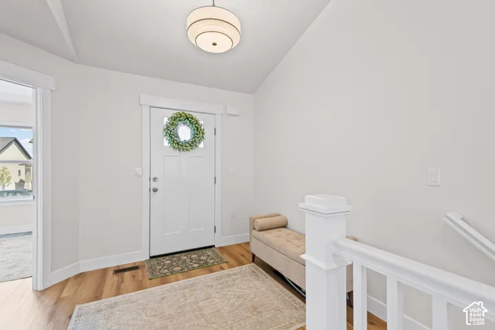 Entryway with wood-finish flooring, white paneled door with glass insert, and a contemporary ceiling light fixture