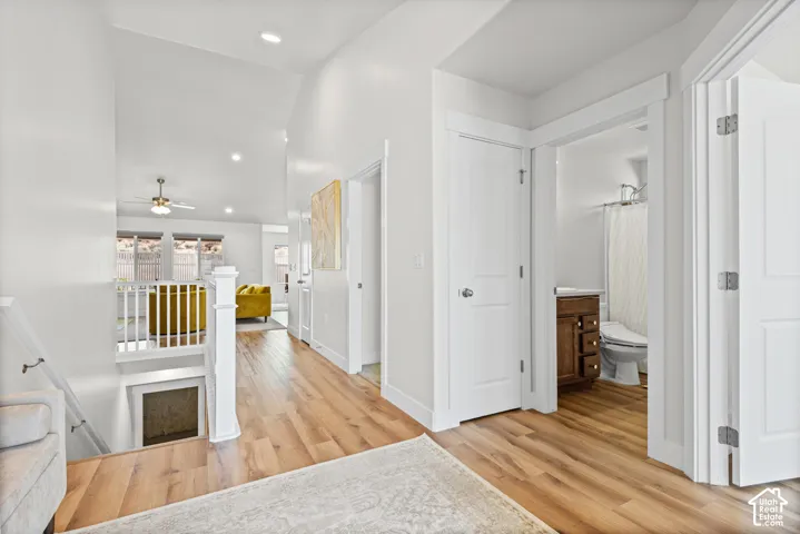 Wood-finish flooring throughout, white painted walls, white trim, and a white staircase with balusters