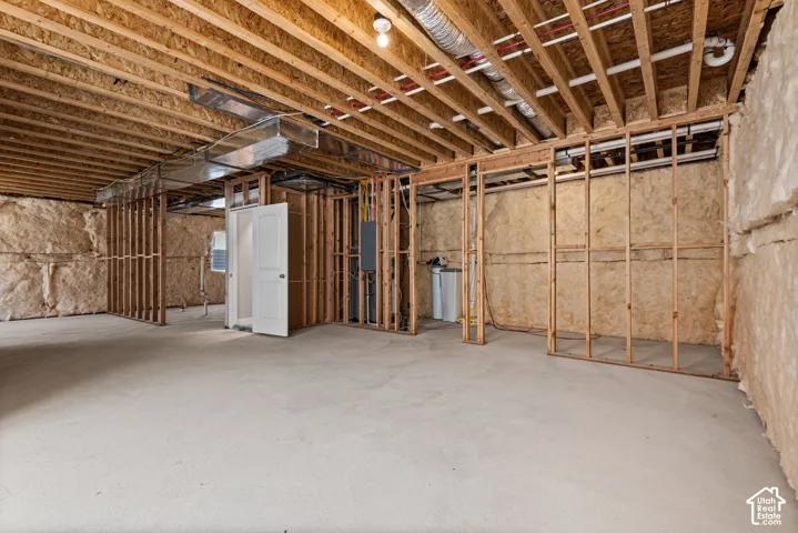 Unfinished basement with exposed ceiling joists, concrete flooring, and insulated walls