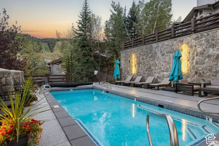 Rectangular swimming pool with a mosaic tile border, surrounded by a stone paver deck
