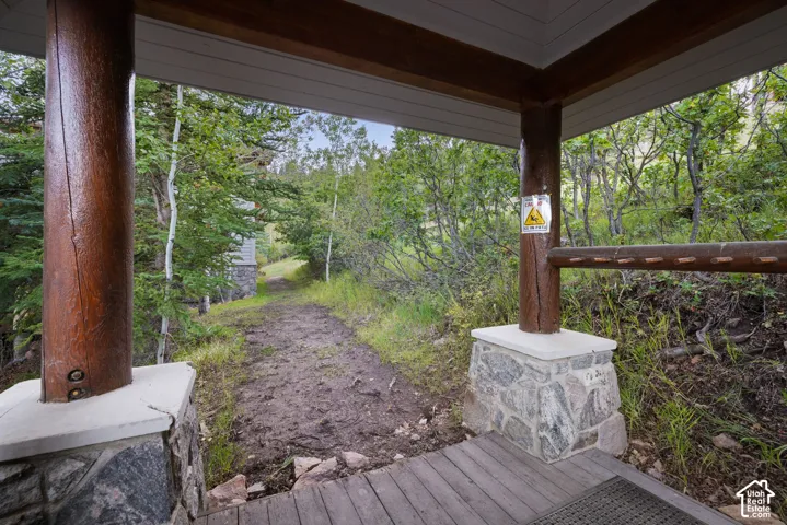 Covered porch with wood-finish decking, stone base columns, and natural wood support beams