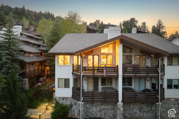 Multi-level exterior with two balconies, a stone foundation, and a gable roofline