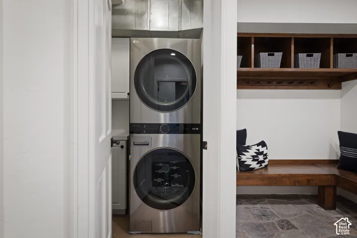 Stackable laundry appliances, built-in wooden shelving, built-in wooden bench seating, wall-mounted coat hooks, natural stone flooring
