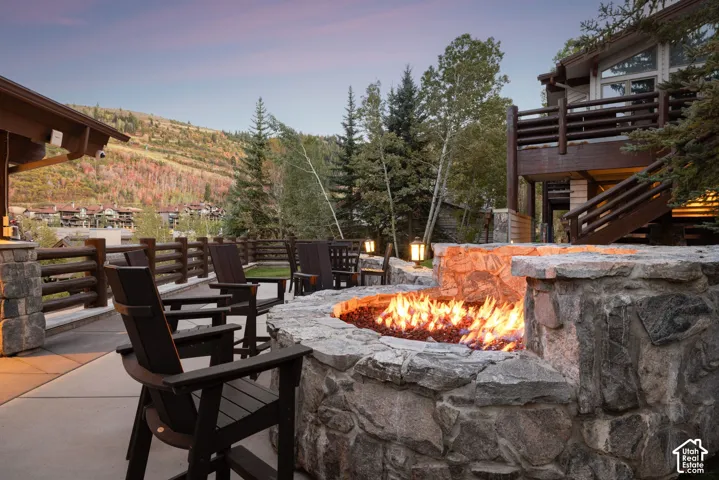 Stone fire pit with integrated stone seating, expansive outdoor patio, and a multi-level deck with wooden railing