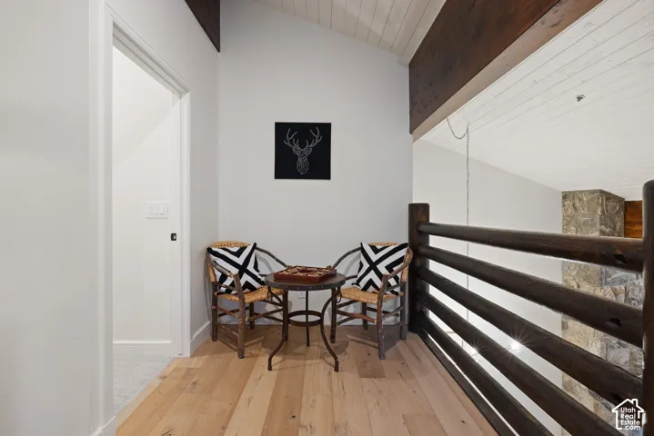 Hardwood flooring, vaulted ceilings with exposed beams, wood-plank ceiling, and a rustic wood railing