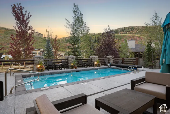 Outdoor pool area featuring a built-in rectangular pool with integrated spa, stone-clad fence posts, and a substantial hardscape surround