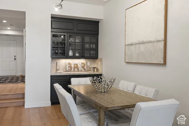 Built-in bar with dark cabinetry, glass-front upper cabinets, and under-cabinet lighting