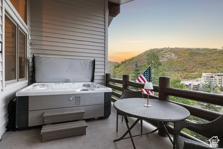 Private balcony featuring a built-in hot tub with steps and a rustic wood railing