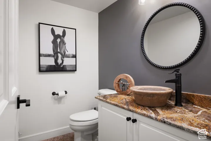 Vanity with a stone vessel sink, granite countertop, and dark-finish faucet