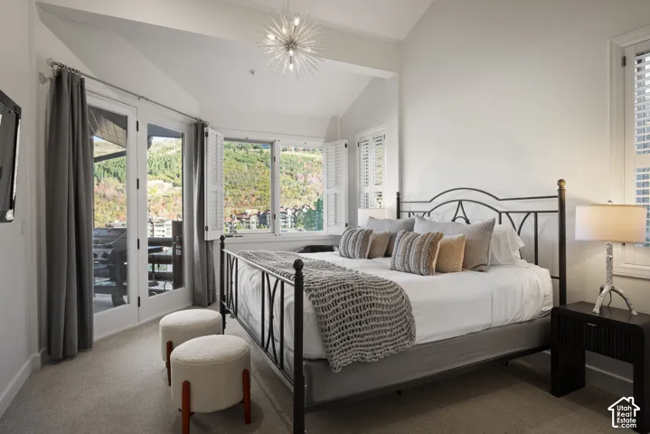 Vaulted ceiling with an attached sputnik chandelier, white plantation shutters, and light gray carpeted flooring