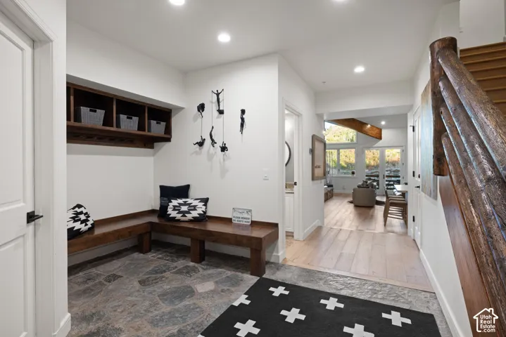 Entryway featuring stone-finish flooring, built-in wooden bench seating, a custom wood shelving unit, and a rustic wood staircase