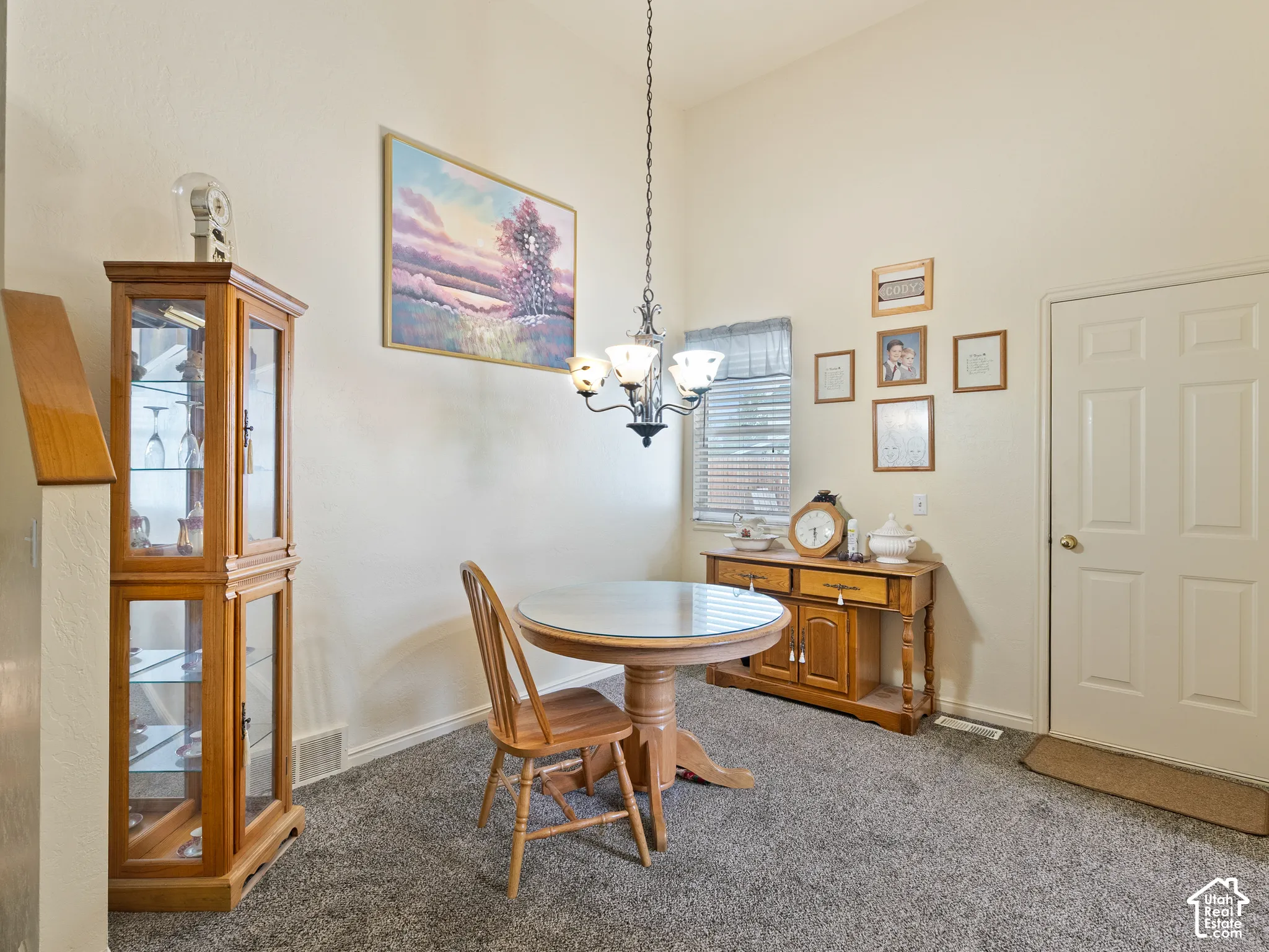 Vaulted ceiling with an attached chandelier, neutral wall paint, and gray carpeting