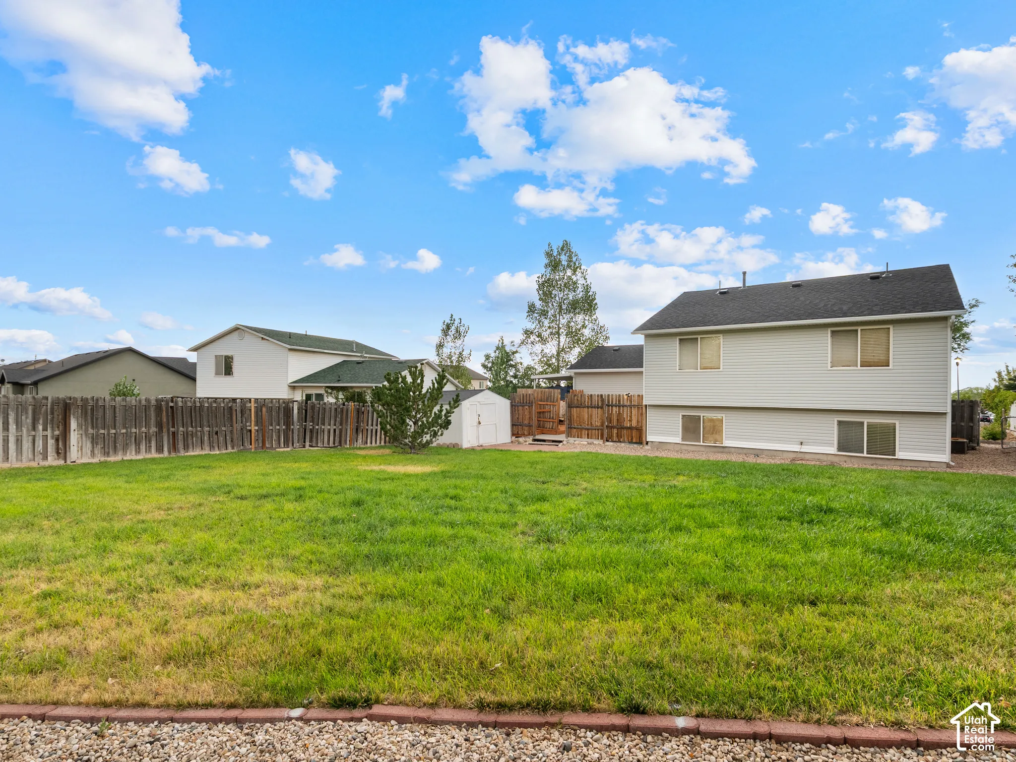Spacious backyard featuring a grass lawn, privacy fencing, and a white storage shed