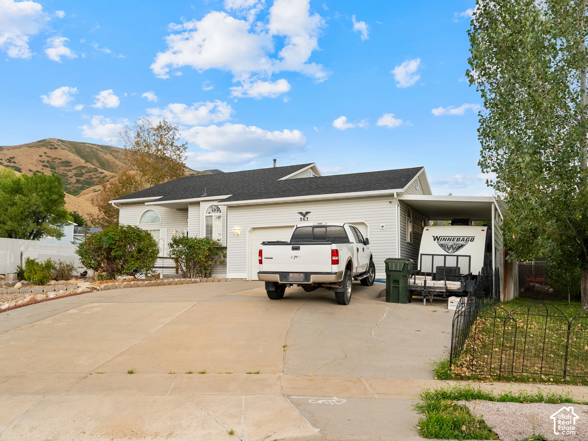 White siding exterior with an attached garage, covered carport, and a concrete driveway