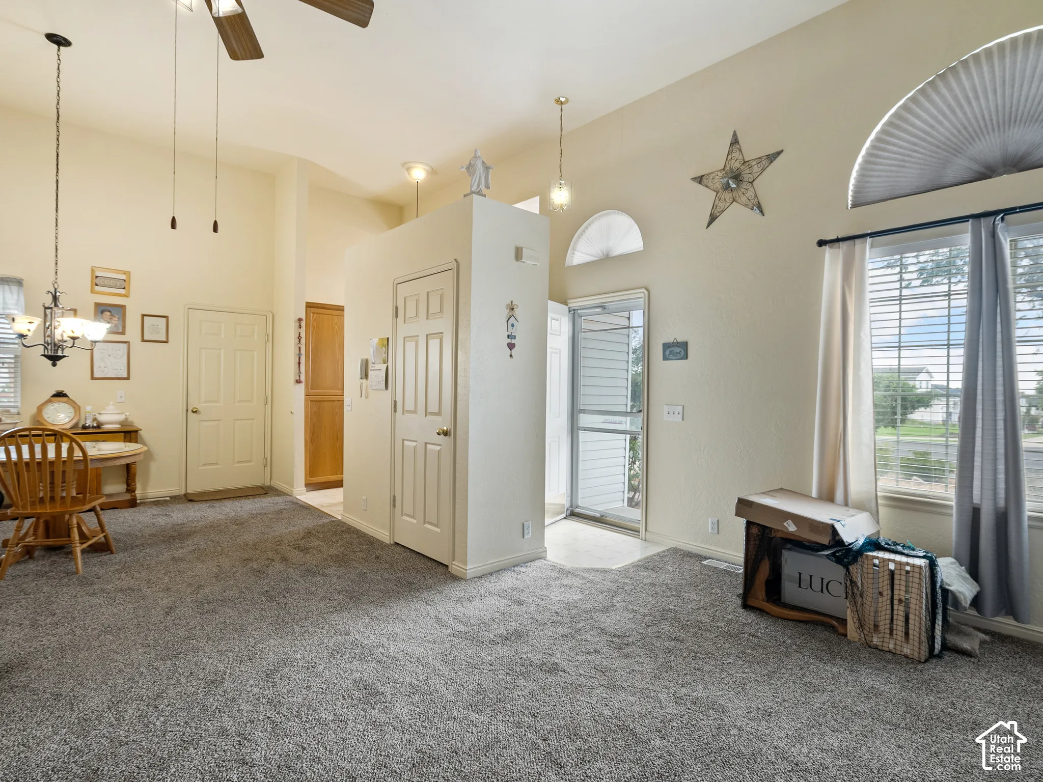 Vaulted ceilings with a ceiling fan, arched transom windows, and light-toned carpeting