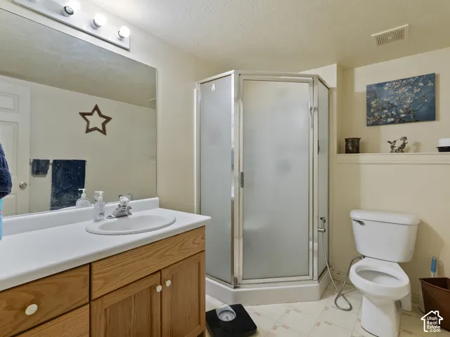 Bathroom featuring a corner shower enclosure with frosted glass, a vanity with a wood-finish cabinet and integrated sink, a wall-mounted mirror, and a toilet