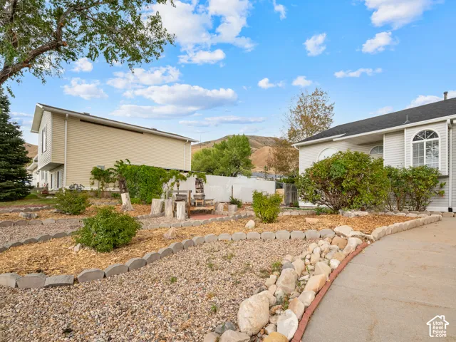 Front yard landscaping with gravel and wood chip beds, concrete curbing, and various shrubs