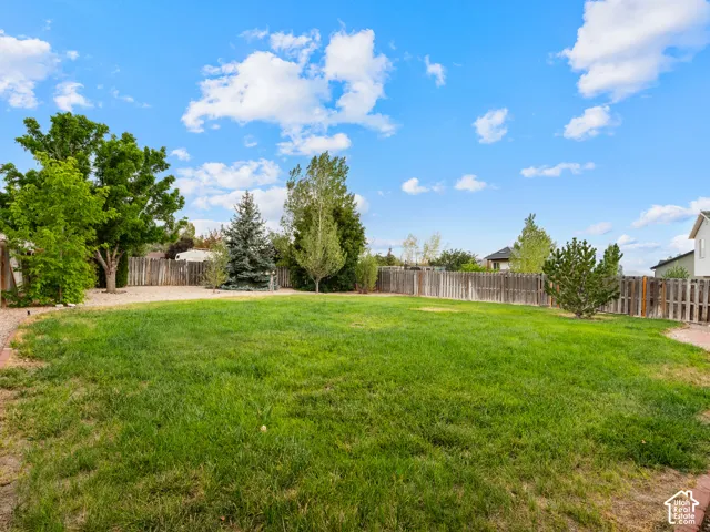 Expansive lawn area with a perimeter wood fence, mature trees, and a brick-lined border