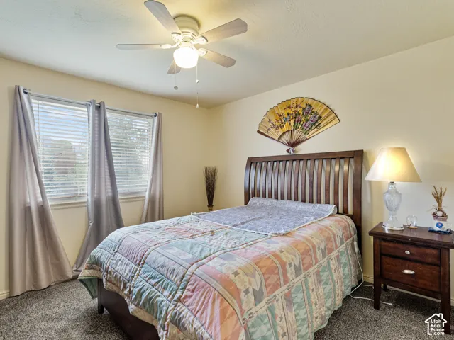 Recessed windows with blinds, ceiling fan, and carpeted flooring