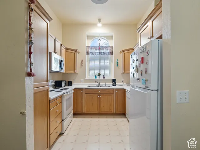 U-shaped kitchen featuring wood cabinetry, white countertops, and a white refrigerator