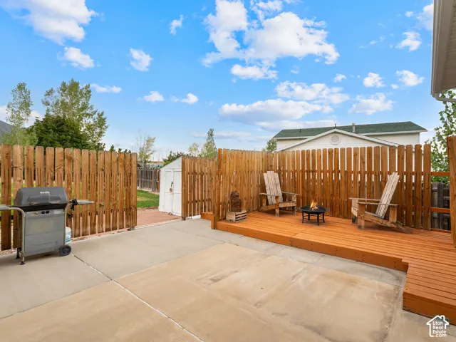 Spacious concrete patio with a raised wood deck, privacy fencing, and an outdoor storage shed
