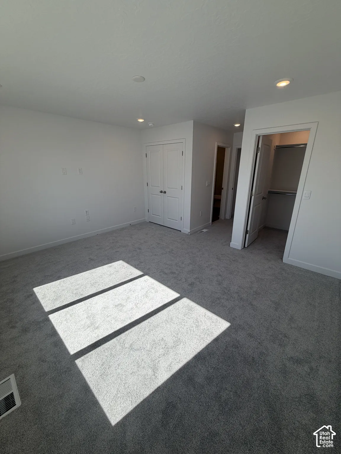 Gray carpeting with white walls, recessed lighting, and a bi-fold closet door