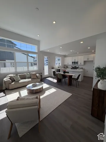 Open concept living area with high ceilings, recessed lighting, expansive windows, wood-finish flooring, and a kitchen island with seating. *Furniture not included.