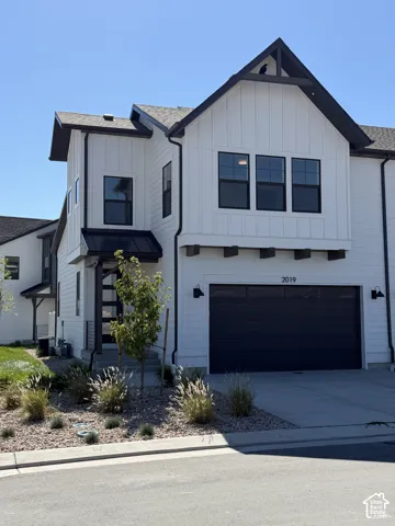 Modern exterior with vertical white siding, black-framed windows, a black garage door, and decorative wood accents