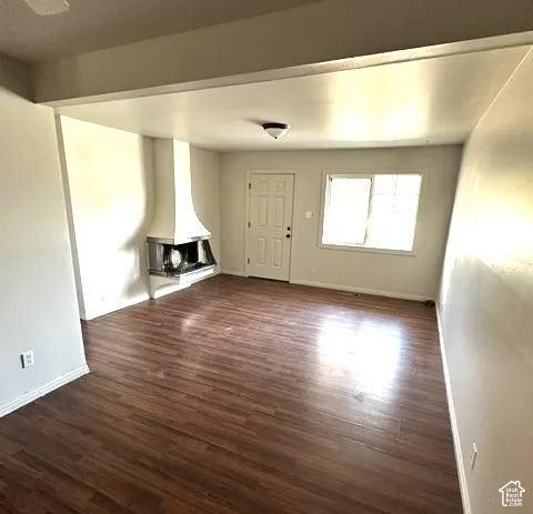 Wood-finish flooring throughout, featuring a modern fireplace with a metal hood and hearth, and a paneled entry door