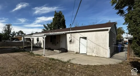 Pitched roofline over the main structure and an attached covered patio with concrete flooring