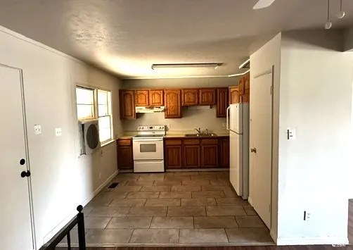Kitchen featuring wood-finish cabinetry, tile flooring, white electric range, and a white refrigerator