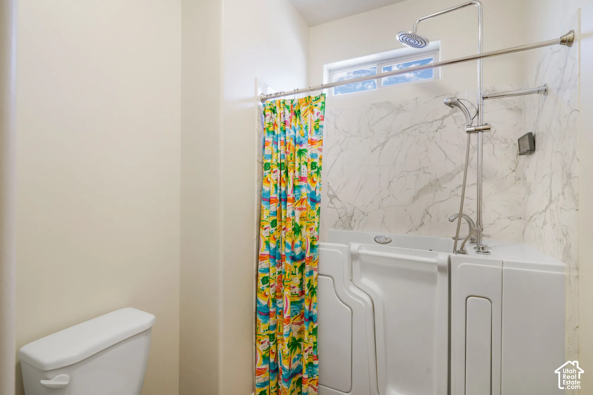 Walk-in therapeutic tub with grab bar, polished chrome fixtures, rain shower head, handheld shower, and marble-patterned wall surround