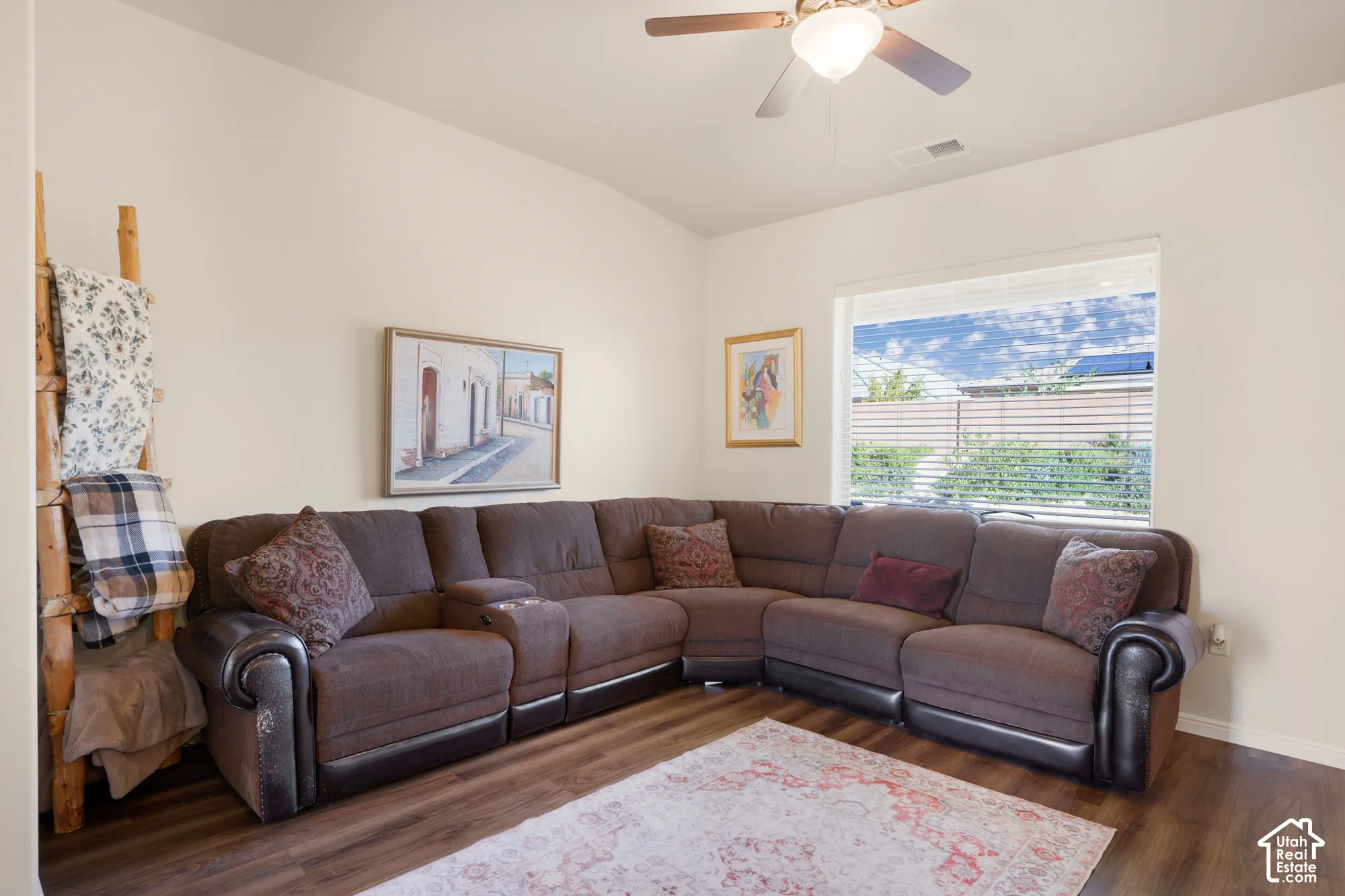 Vaulted ceilings, wood-finish flooring, a ceiling fan, and a large window with horizontal blinds