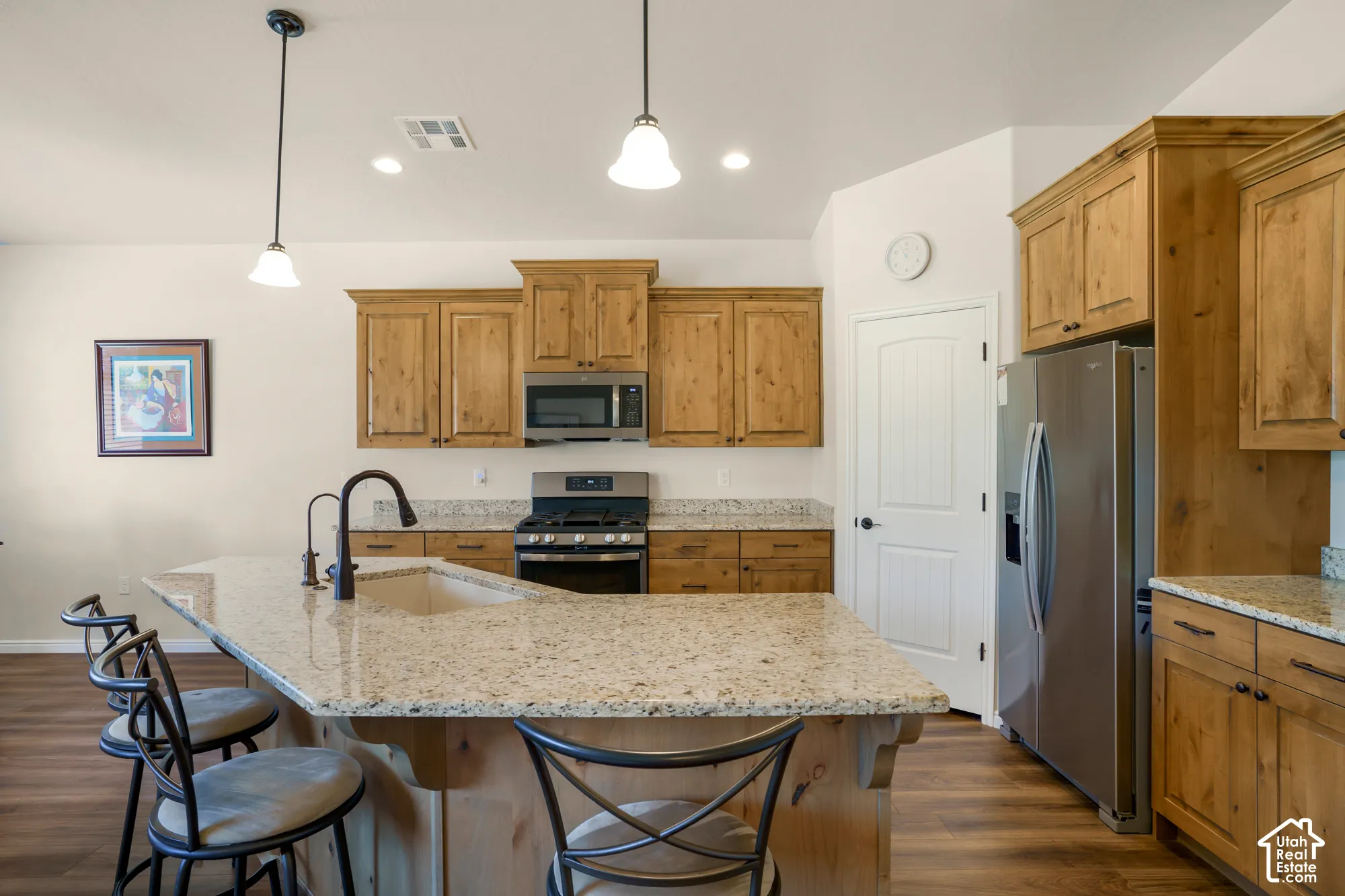 Kitchen featuring warm wood cabinetry, stainless steel appliances including a gas range, and a large granite countertops