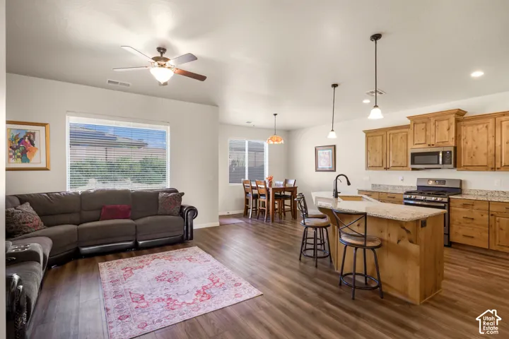Open-concept living and dining area featuring hardwood flooring, a curved sectional sofa arrangement, and pendant lighting