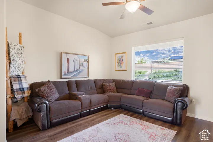 Vaulted ceilings, wood-finish flooring, a ceiling fan, and a large window with horizontal blinds