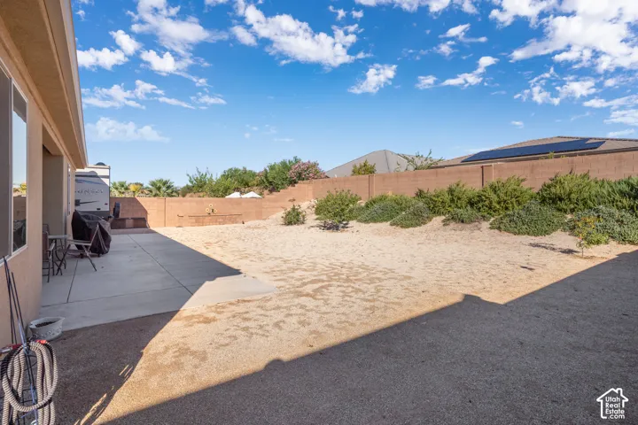 Expansive outdoor space featuring a concrete patio, a low-maintenance gravel area, and a privacy wall