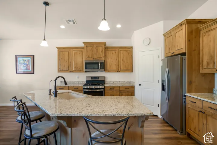 Kitchen featuring warm wood cabinetry, stainless steel appliances including a gas range, and a large granite countertops