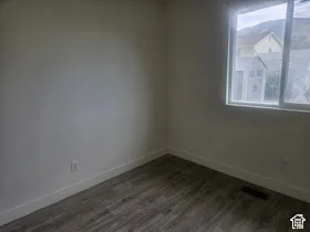 Wood-finish flooring with white baseboards and a large window