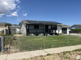 White exterior with a covered porch, solar panels, and an attached garage